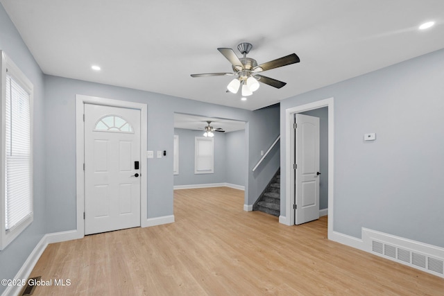 entrance foyer with ceiling fan, light wood-style flooring, visible vents, stairs, and baseboards