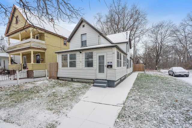 view of front of property with entry steps, fence, and a balcony