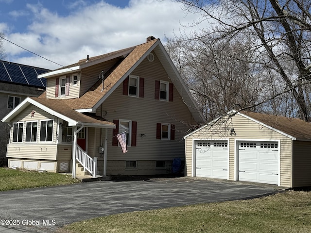 view of front of house with roof with shingles, an outdoor structure, a garage, and a chimney