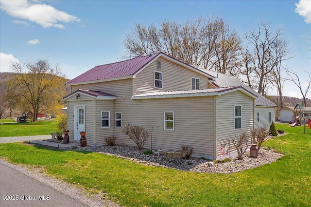 view of home's exterior with metal roof and a lawn