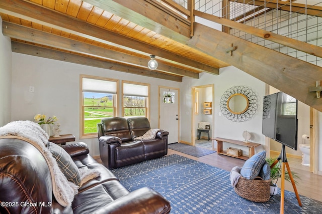 living room featuring baseboards, a wealth of natural light, beam ceiling, and wood finished floors
