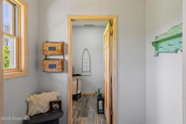 corridor featuring visible vents, baseboards, and wood finished floors