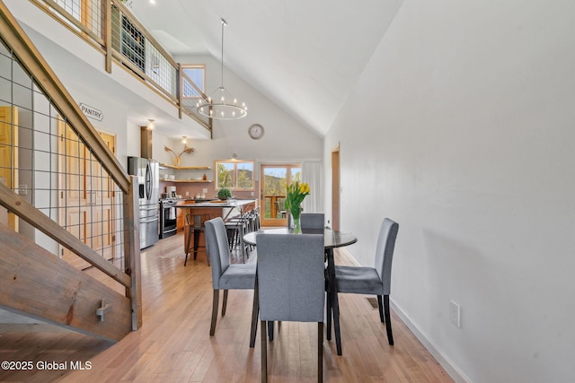 dining room featuring stairs, high vaulted ceiling, a notable chandelier, and light wood finished floors