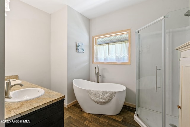 bathroom featuring baseboards, a shower stall, a sink, and wood finished floors