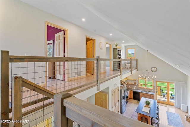 hall with an inviting chandelier, high vaulted ceiling, recessed lighting, and wood finished floors