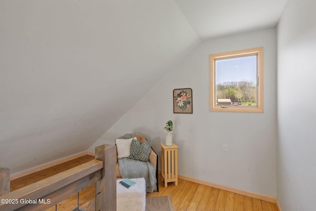 living area featuring baseboards, vaulted ceiling, and light wood finished floors