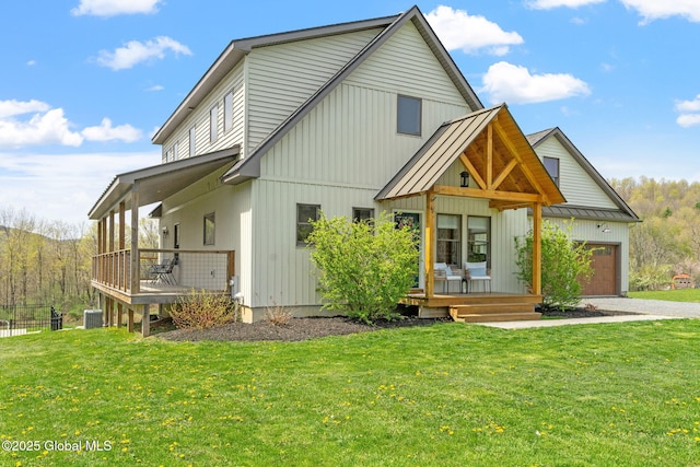 back of house with a lawn, an attached garage, and a wooden deck