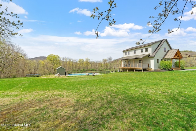 view of yard with an outdoor structure, an outdoor pool, a shed, and a deck