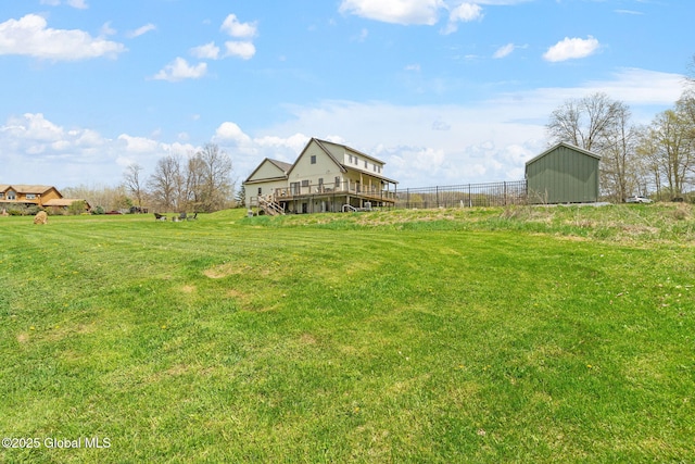 view of yard featuring fence, a storage unit, and an outbuilding