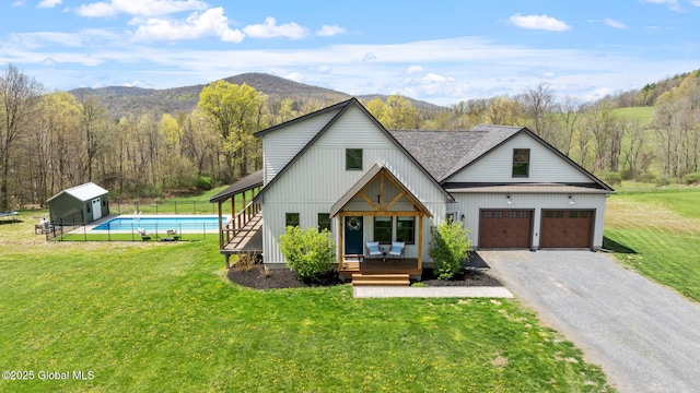 view of front of home featuring fence, a deck with mountain view, driveway, and a front yard