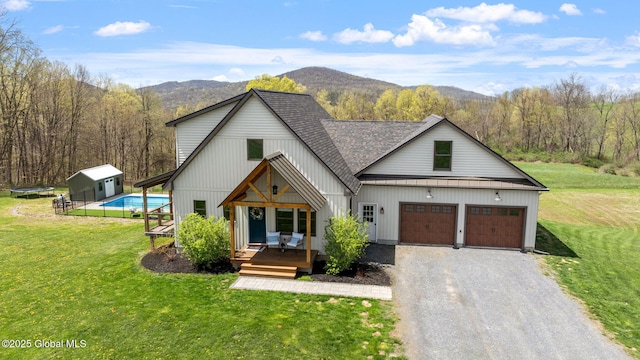 view of front of property featuring a storage shed, a mountain view, a front yard, and gravel driveway