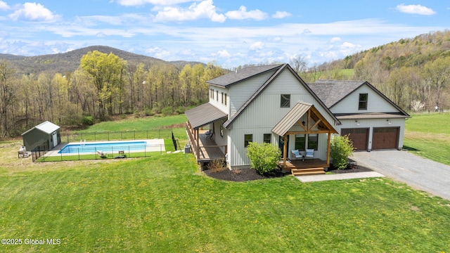 view of front of property featuring a view of trees, fence, and a front lawn