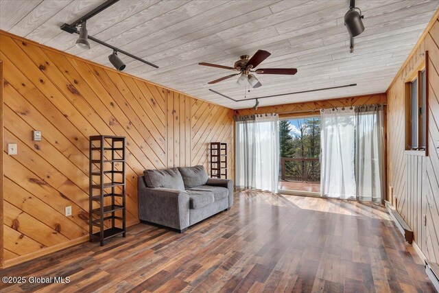 living area with track lighting, wood walls, wood finished floors, wood ceiling, and a ceiling fan
