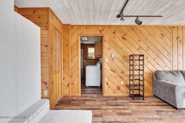 sitting room featuring washer / dryer, wooden walls, rail lighting, and wood finished floors