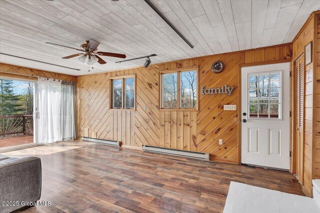 interior space with plenty of natural light, a baseboard heating unit, and wood finished floors