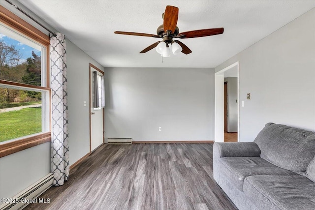 sitting room featuring baseboard heating, wood finished floors, and a wealth of natural light