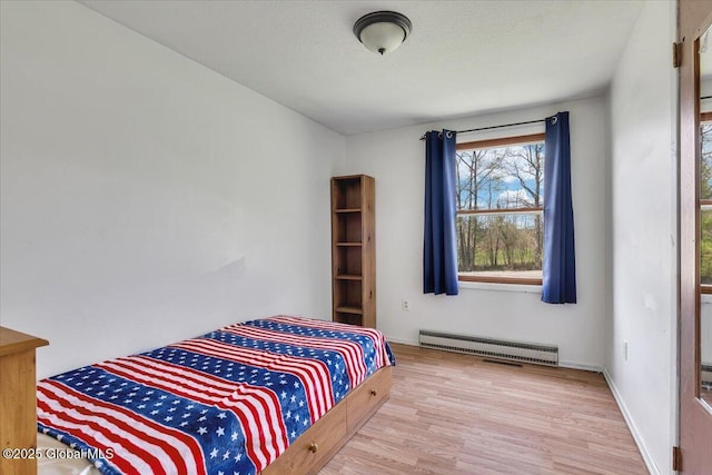 bedroom featuring baseboard heating, baseboards, and wood finished floors