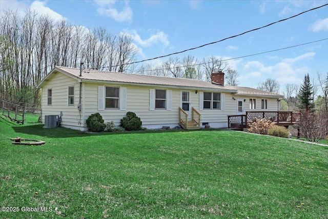 ranch-style home with a front lawn, a deck, a chimney, and metal roof