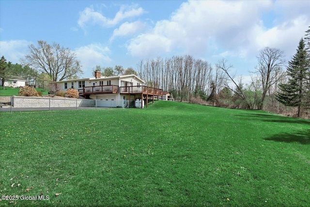 view of yard featuring fence, a wooden deck, and a garage