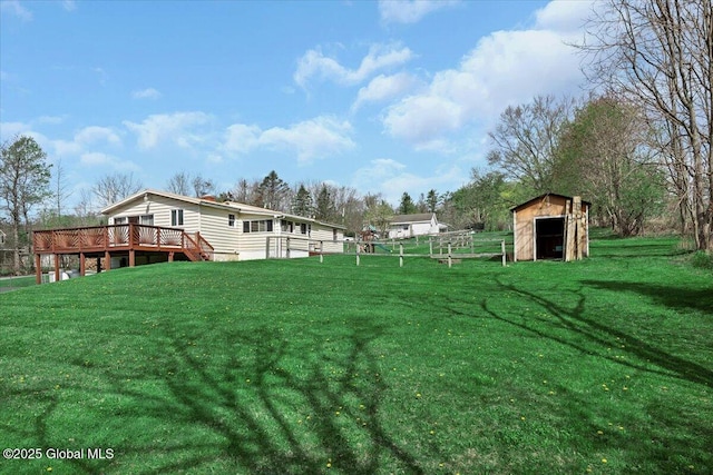 view of yard featuring fence, a wooden deck, an outdoor structure, and a storage unit