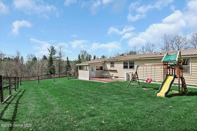 rear view of house featuring a lawn, fence, and a playground