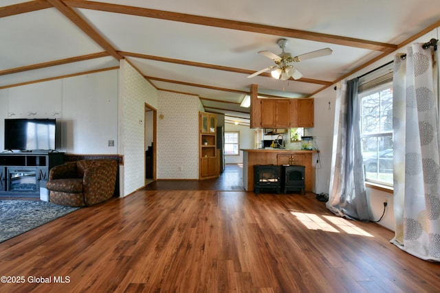 unfurnished living room with ceiling fan, wood finished floors, and lofted ceiling with beams