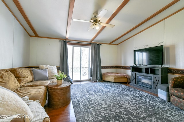 living area featuring a glass covered fireplace, vaulted ceiling, a ceiling fan, crown molding, and wood finished floors