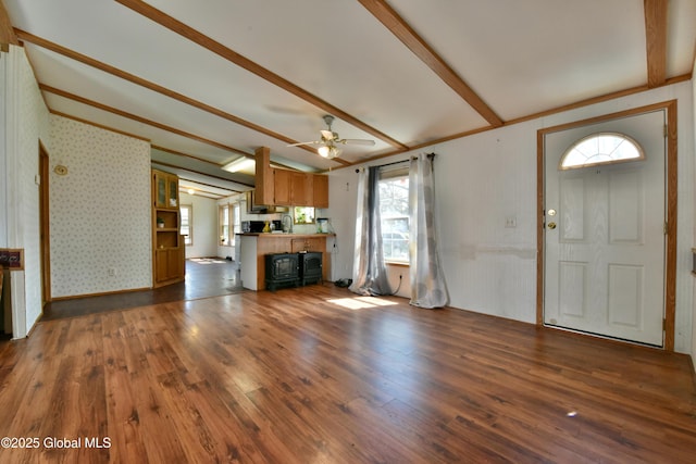 unfurnished living room featuring beamed ceiling, a ceiling fan, and wood finished floors
