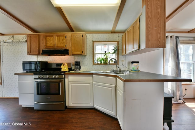 kitchen featuring stainless steel gas range, under cabinet range hood, black microwave, wallpapered walls, and dark wood-type flooring