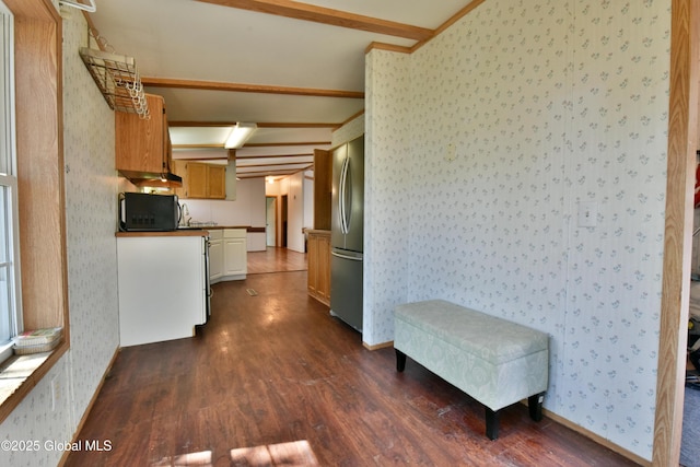 kitchen featuring wallpapered walls, lofted ceiling with beams, stainless steel fridge, black microwave, and dark wood-type flooring