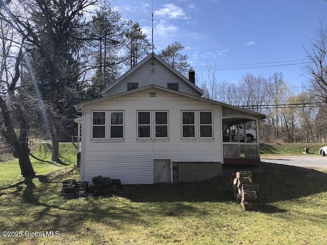view of side of home with a chimney and a lawn