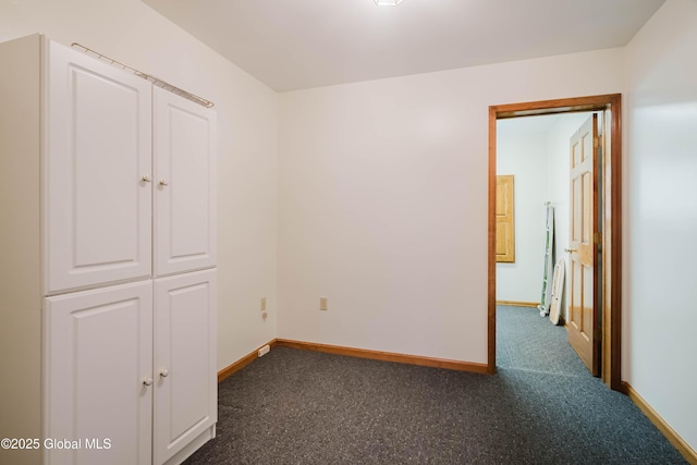 unfurnished bedroom with baseboards and dark carpet