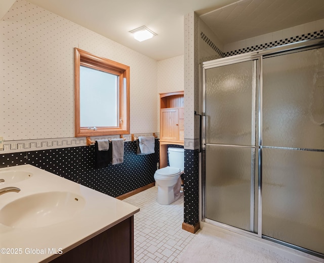 full bath featuring a sink, a stall shower, wallpapered walls, and double vanity