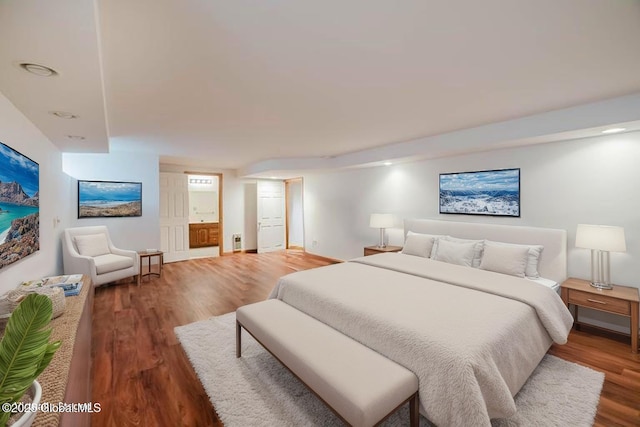 bedroom with baseboards, wood finished floors, and ensuite bathroom