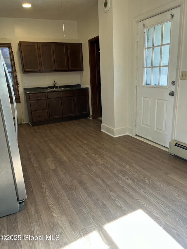 kitchen featuring a sink, dark brown cabinetry, dark wood-style floors, and freestanding refrigerator