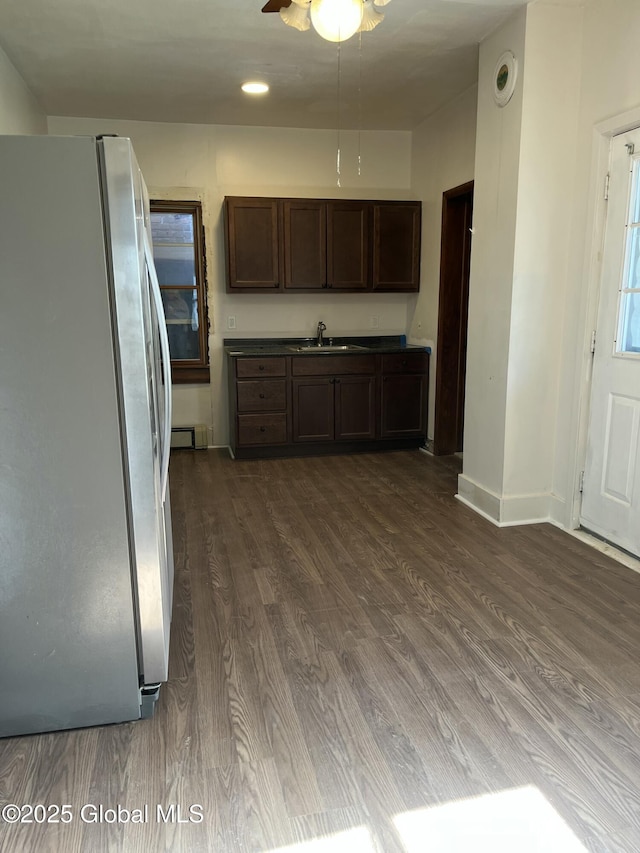 kitchen with dark brown cabinetry, ceiling fan, dark wood finished floors, freestanding refrigerator, and baseboards