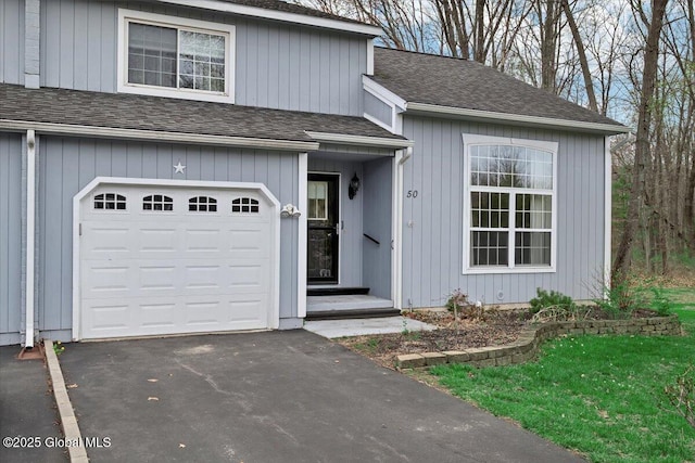 view of front of house with an attached garage, a shingled roof, and aphalt driveway