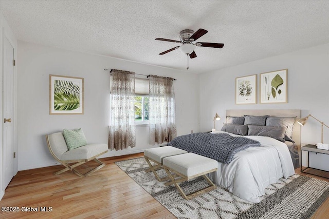 bedroom featuring a ceiling fan, light wood-type flooring, and a textured ceiling