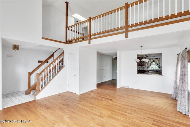 unfurnished living room featuring a high ceiling, stairs, and wood finished floors