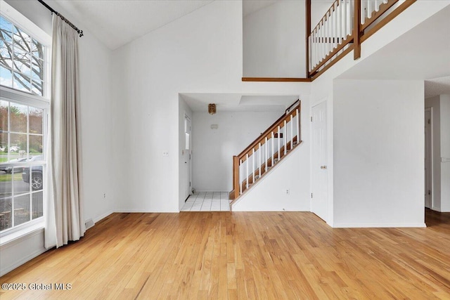 entrance foyer featuring a healthy amount of sunlight, hardwood / wood-style flooring, stairs, and a towering ceiling