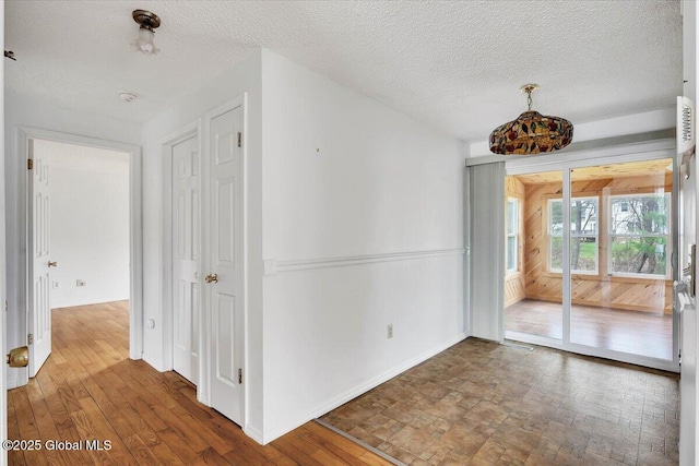 empty room with baseboards, a textured ceiling, and wood finished floors