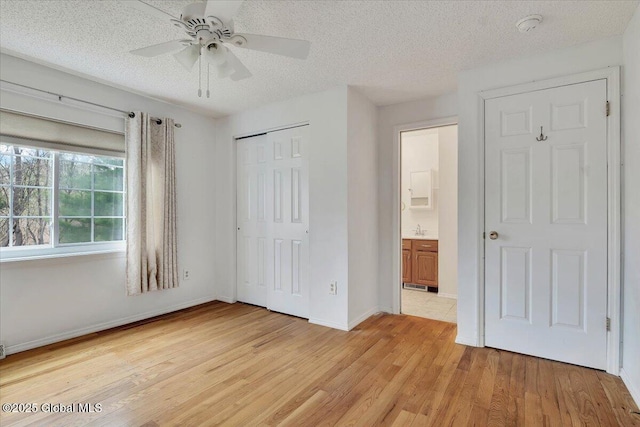 unfurnished bedroom with baseboards, a textured ceiling, light wood-style flooring, and a closet