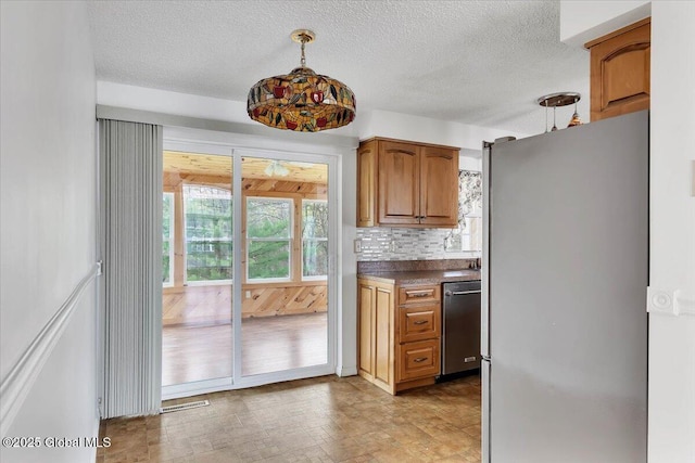 kitchen with decorative backsplash, dark countertops, a textured ceiling, brown cabinets, and appliances with stainless steel finishes