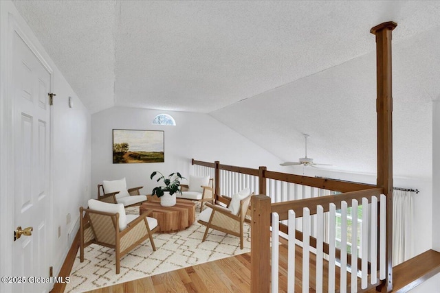 living area with a textured ceiling, light wood finished floors, and vaulted ceiling