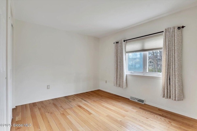 spare room featuring wood-type flooring, baseboards, and visible vents