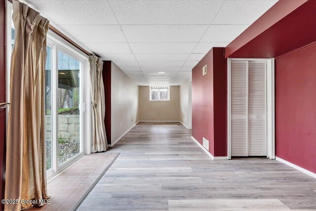 hall featuring visible vents, baseboards, a paneled ceiling, and wood finished floors