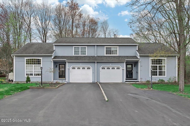 traditional home with a garage, roof with shingles, and driveway