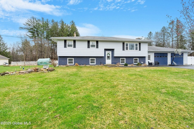 split foyer home featuring driveway, a garage, fence, and a front lawn
