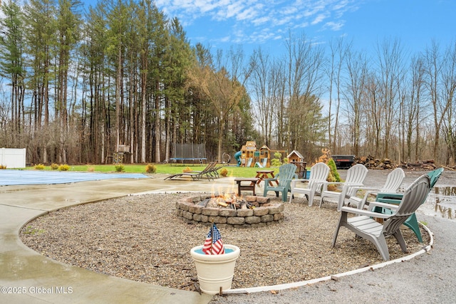 view of playground featuring a patio area, an outdoor fire pit, and a trampoline