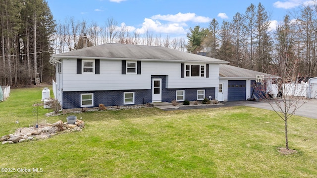bi-level home with a chimney, driveway, a front lawn, a garage, and fence